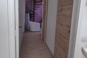 Stylish hallway leading to a cozy room with a comfortable chair and a staircase to the upper floor.