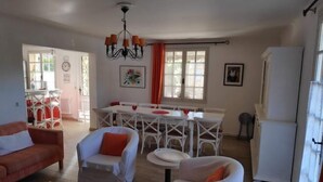 A cozy living room with a sofa, armchairs, and a dining area with a table and chairs. - Villa les Carlets (Saignon)