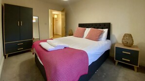 A bedroom with a bed, a wardrobe, a bedside table, and a lamp.