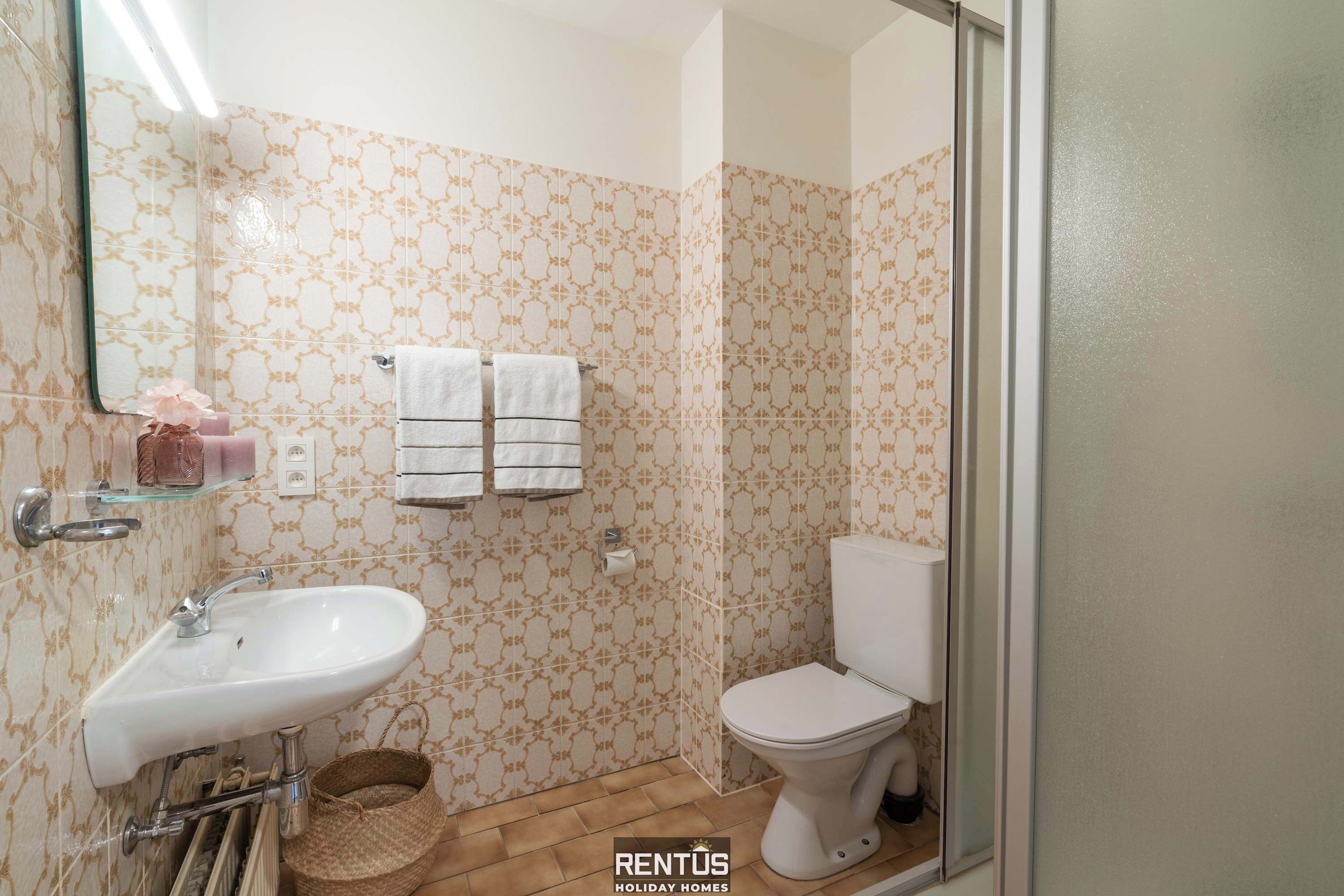 Een badkamer met een wastafel, twee handdoeken, een toilet en een douche.