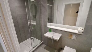 Ein modernes Badezimmer mit Duschkabine aus Glas, einem weißen Waschbecken und einer Toilette.