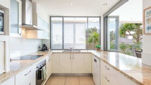 A modern kitchen with a large window, built-in oven, and a dishwasher. - Zinc One Select - Oceanstays - ocean views (Yamba)
