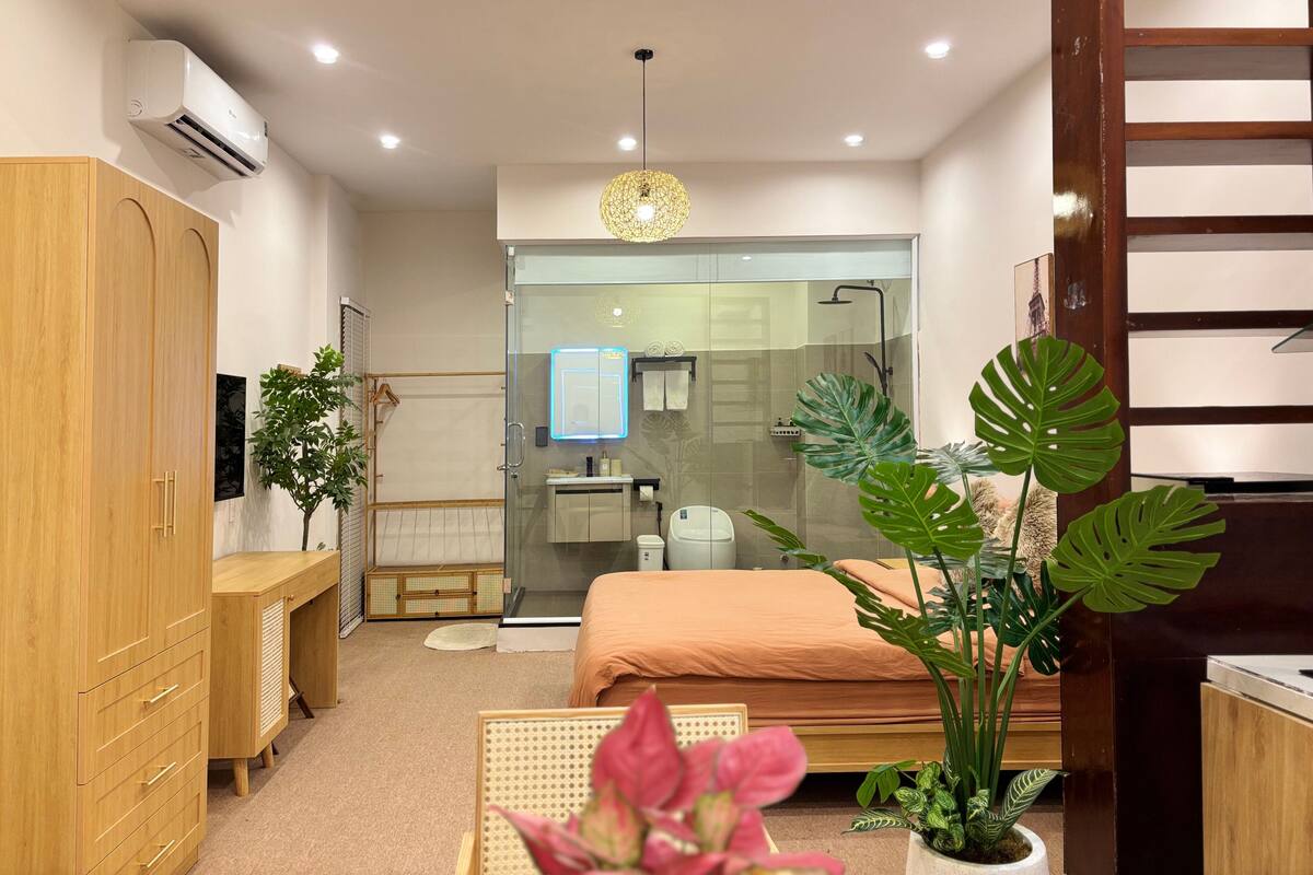 Un dormitorio moderno con cama, mesita de noche, armario y zona de ducha visible a través de una puerta de cristal.