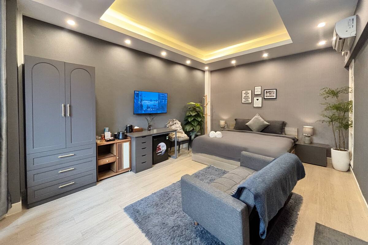 Un dormitorio moderno con cama, mesitas de noche, televisión y armario.