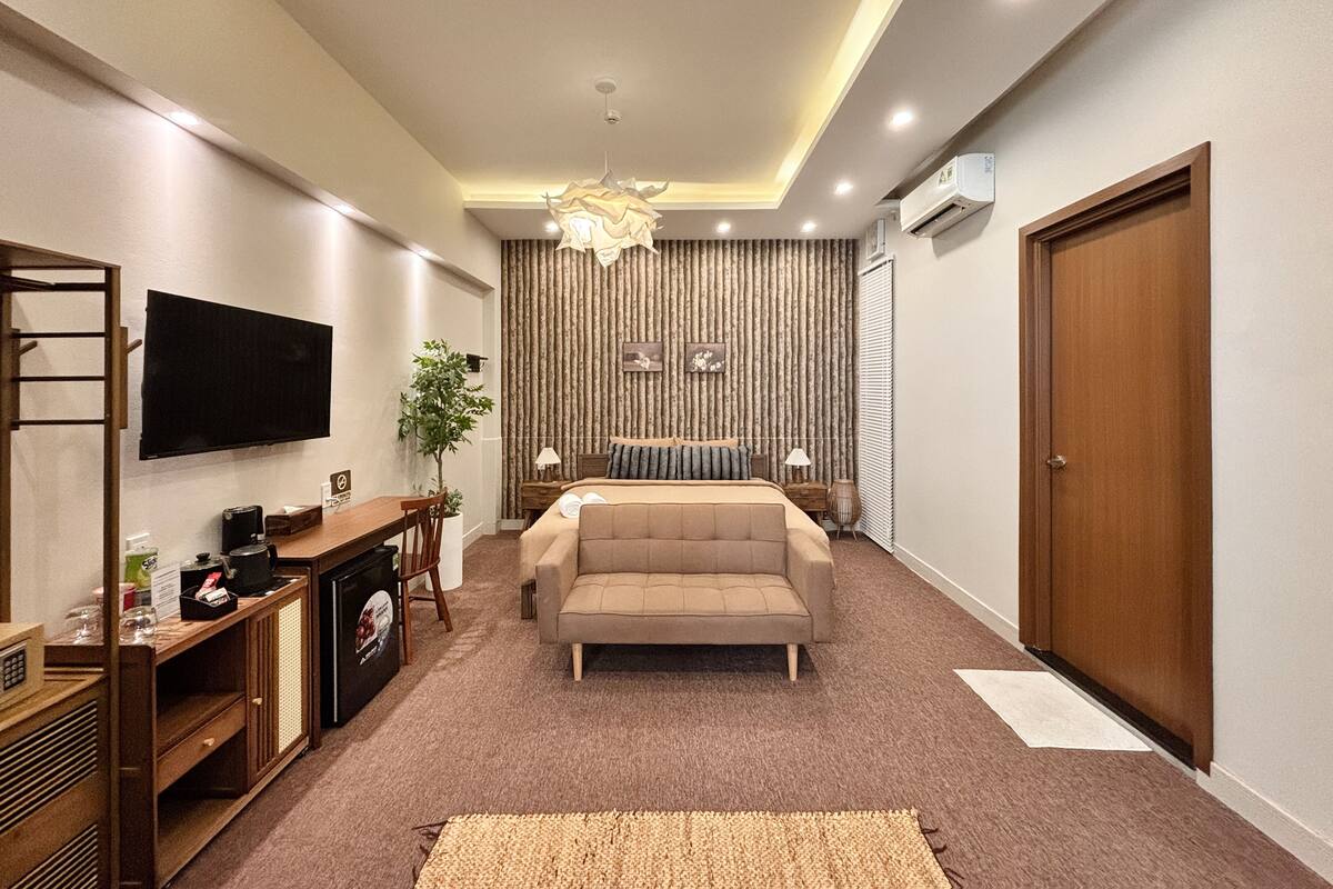 Una habitación de hotel moderna con una cama grande, un televisor, una cafetera y un escritorio con una computadora.