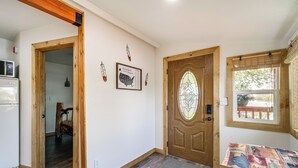A wooden-framed doorway leading to a room with a wooden floor, a door with a stained glass design, and a wall-mounted map of the United States. - 'Crater Lake' Williamson River Resort Cabin 6 (Chiloquin)
