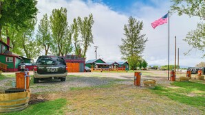 A rustic campground with a gravel path, wooden barrels, and a parked SUV. - 'Crater Lake' Williamson River Resort Cabin 6 (Chiloquin)
