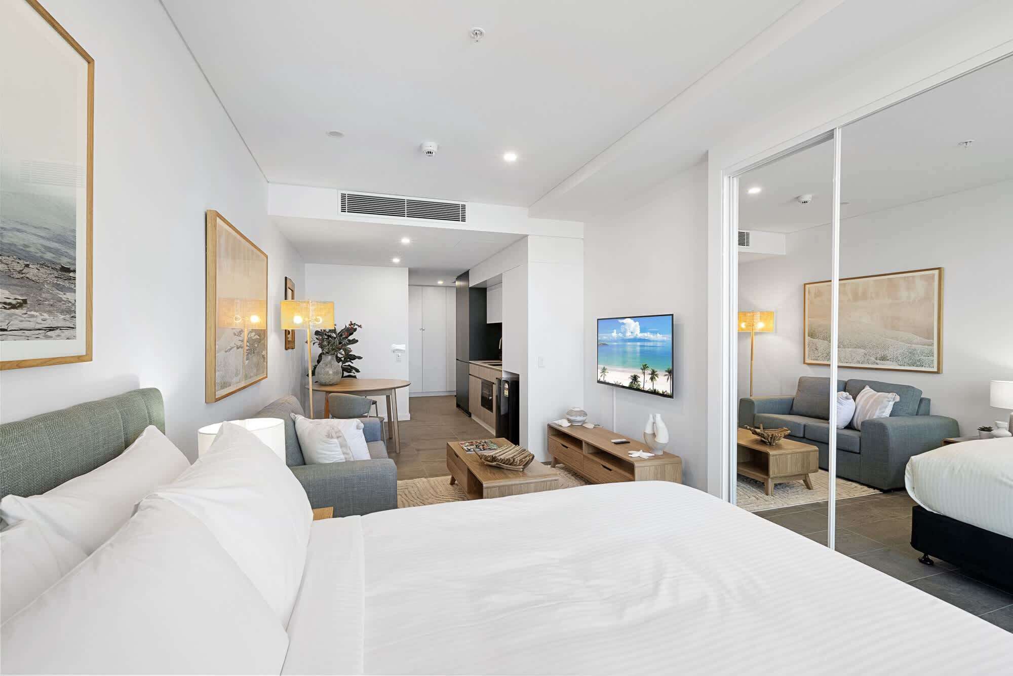 A hotel room with a large bed, a seating area with a table, a television, and artwork on the walls.