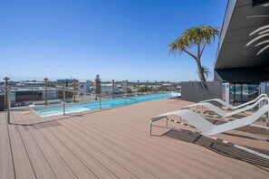 A rooftop pool area with lounge chairs and a view of the cityscape.