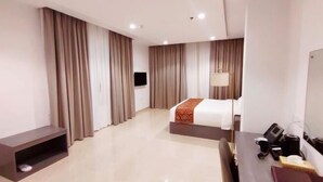 Una habitación de hotel con cama, escritorio, computadora, televisor y cafetera.