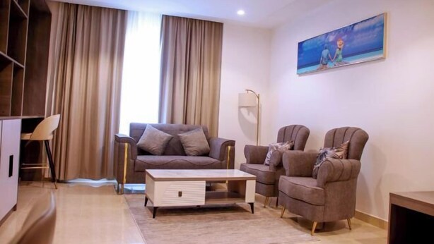 Una sala de estar moderna con un sofá, dos sillones, una mesa de centro y un cuadro en la pared.