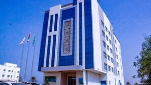 Un edificio moderno con un diseño vertical llamativo, múltiples ventanales y un elemento decorativo central.