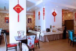 A restaurant with tables and chairs, a buffet area, and red decorations. - Wave View Hotel (Seeb)