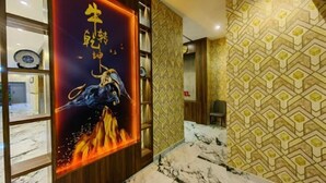 Un pasillo con una decoración mural que muestra un toro y llamas, papel tapiz estampado y suelo de mármol.