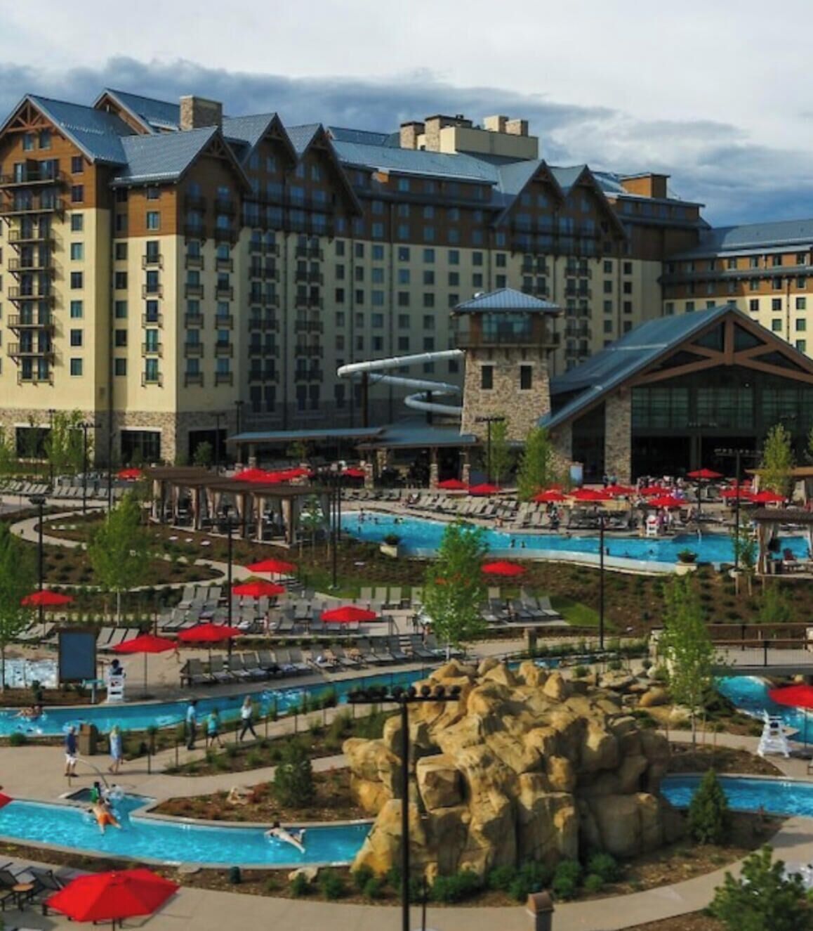 A hotel with multiple swimming pools, outdoor seating areas, and a large building with a distinctive architectural style.