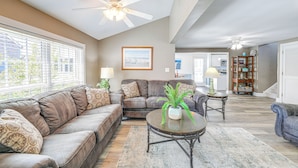 A spacious living room with a brown leather sofa, a round coffee table with a potted plant, and a ceiling fan. - Steps to Shore: Newly Renovated Dewey Beach Home! (Dewey Beach)