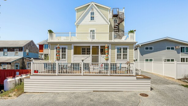 A two-story house with a balcony, a staircase, and a fenced front yard. - Steps to Shore: Newly Renovated Dewey Beach Home! (Dewey Beach)