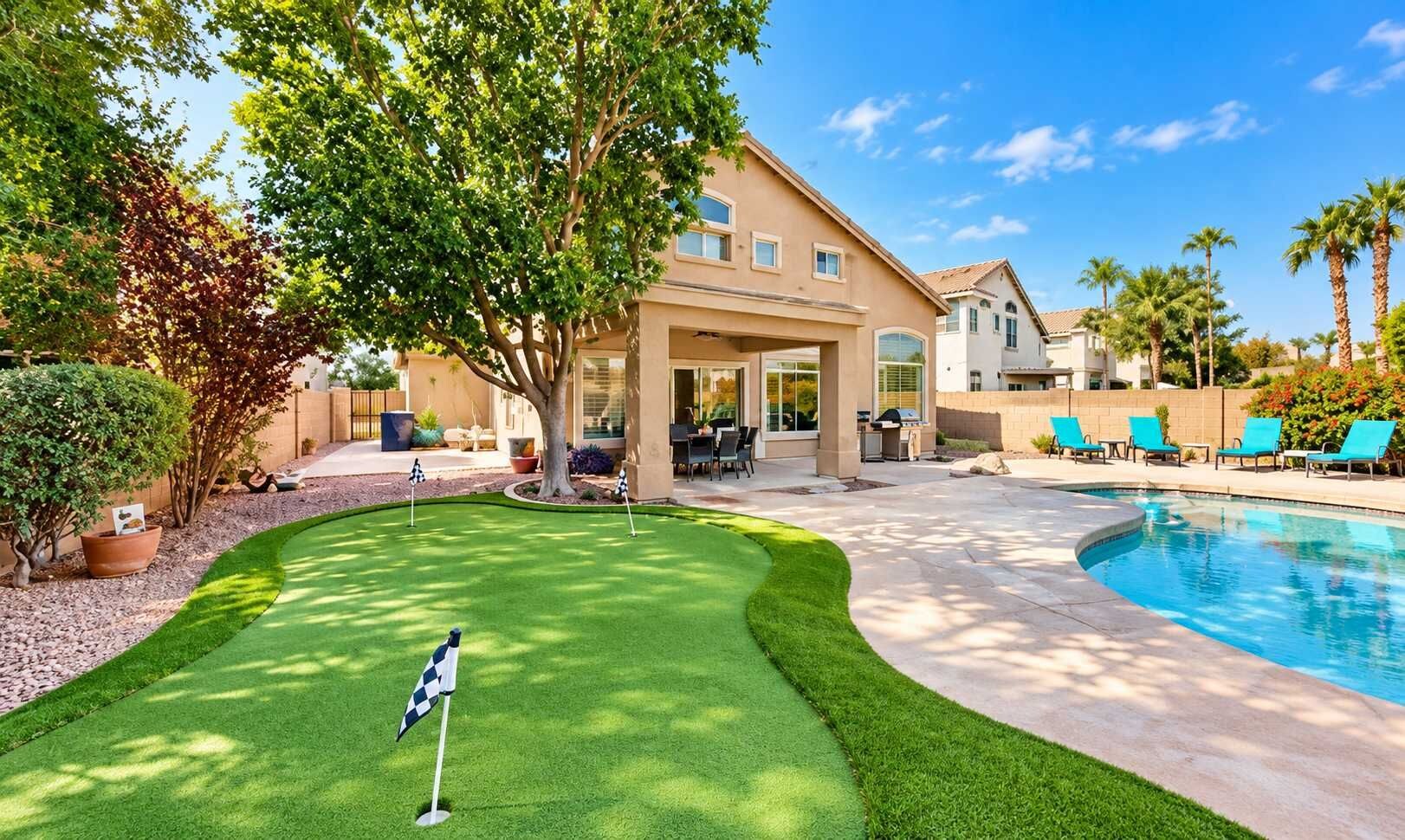 A residential property with a swimming pool, a backyard with a putting green, and a covered patio area.