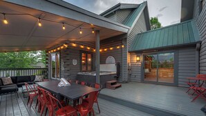 Une terrasse extérieure couverte, équipée d’une table et de chaises, d’un barbecue et d’un coin salon.