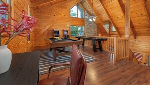 Un intérieur en bois agrémenté d’une table de billard, d’une table de jeu de fléchettes et d’une cheminée en pierre.