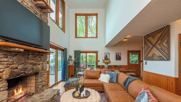 A spacious living room with a stone fireplace, a large sectional sofa, and a cozy seating area. - Sleeps 20! Hot Tub~Outdoor Theater~Fire Pit~Games (Fairview)
