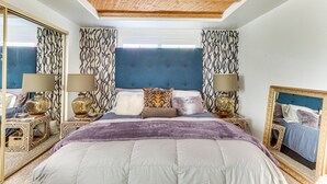 A bedroom with a large bed, two bedside tables with lamps, a mirror, and patterned curtains. - 2 Mi to Dtwn Palm Springs: Mtn-View Condo w/ Pool (Palm Springs)