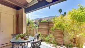 A patio with a round table and chairs, surrounded by plants and a wooden fence. - 2 Mi to Dtwn Palm Springs: Mtn-View Condo w/ Pool (Palm Springs)