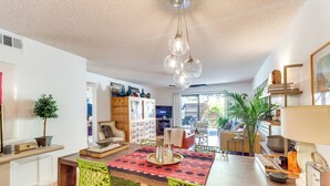 A modern kitchen with a dining area, featuring a wooden table, green chairs, and a red patterned tablecloth. - 2 Mi to Dtwn Palm Springs: Mtn-View Condo w/ Pool (Palm Springs)