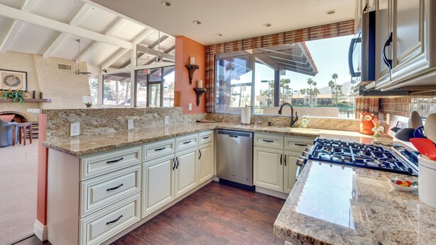 A modern kitchen with granite countertops, stainless steel appliances, and a view of palm trees. - 2 Mi to Dtwn Palm Springs: Mtn-View Condo w/ Pool (Palm Springs)