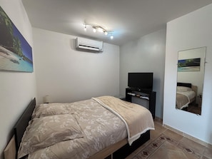 Ein Schlafzimmer mit Bett, Fernseher, Klimaanlage und Spiegel.