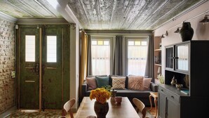 A dining area with a wooden table, chairs, a vase of flowers, and a brick wall. - Charming 2-bedroom house with WiFi and AC in vibrant Istanbul (Unknown)
