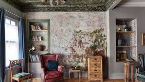 A room with a rustic aesthetic, featuring a distressed wall, wooden furniture, and a variety of decorative items. - Charming 2-bedroom house with WiFi and AC in vibrant Istanbul (Unknown)