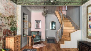 A cozy interior with a wooden staircase, a vintage chair, and a rustic wall. - Charming 2-bedroom house with WiFi and AC in vibrant Istanbul (Unknown)