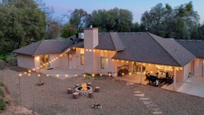 Ein Haus mit überdachter Terrasse, Feuerstelle und Lichterkette.