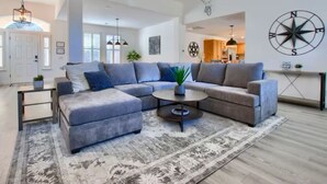Ein modernes Wohnzimmer mit einem grauen Ecksofa, einem Couchtisch und einem gemusterten Teppich.