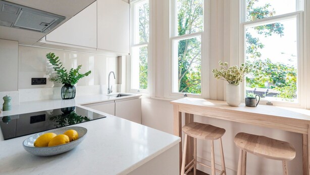 Una cocina moderna con armarios blancos, una estufa negra y un tazón de limones en la encimera.