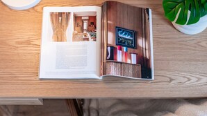Un libro abierto a una página con una fotografía de una habitación, un cuadro enmarcado y una planta en maceta.