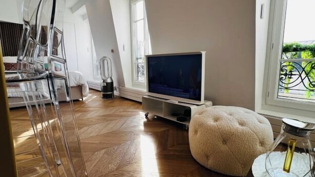 Ett modernt vardagsrum med en platt-TV, ett soffbord i glas och en soffa.