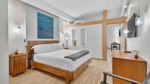 A modern bedroom with a wooden bed, bedside tables, a desk, and a TV.