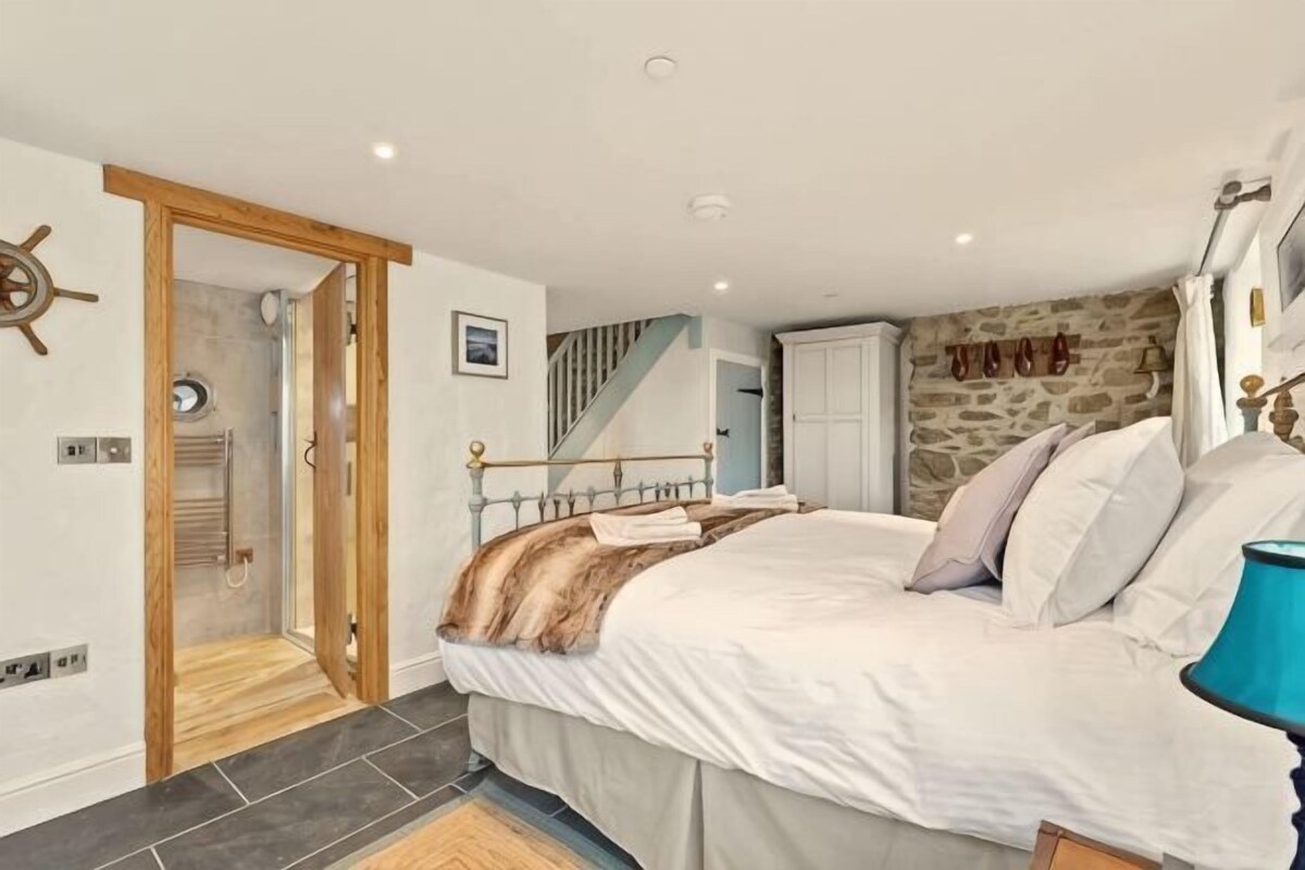 Une chambre à coucher avec un lit, une porte en bois, un escalier et un mur en pierre.