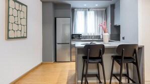 Eine moderne Küche mit Einbaukühlschrank, einer Mikrowelle und einer Essecke mit zwei Barhocker.