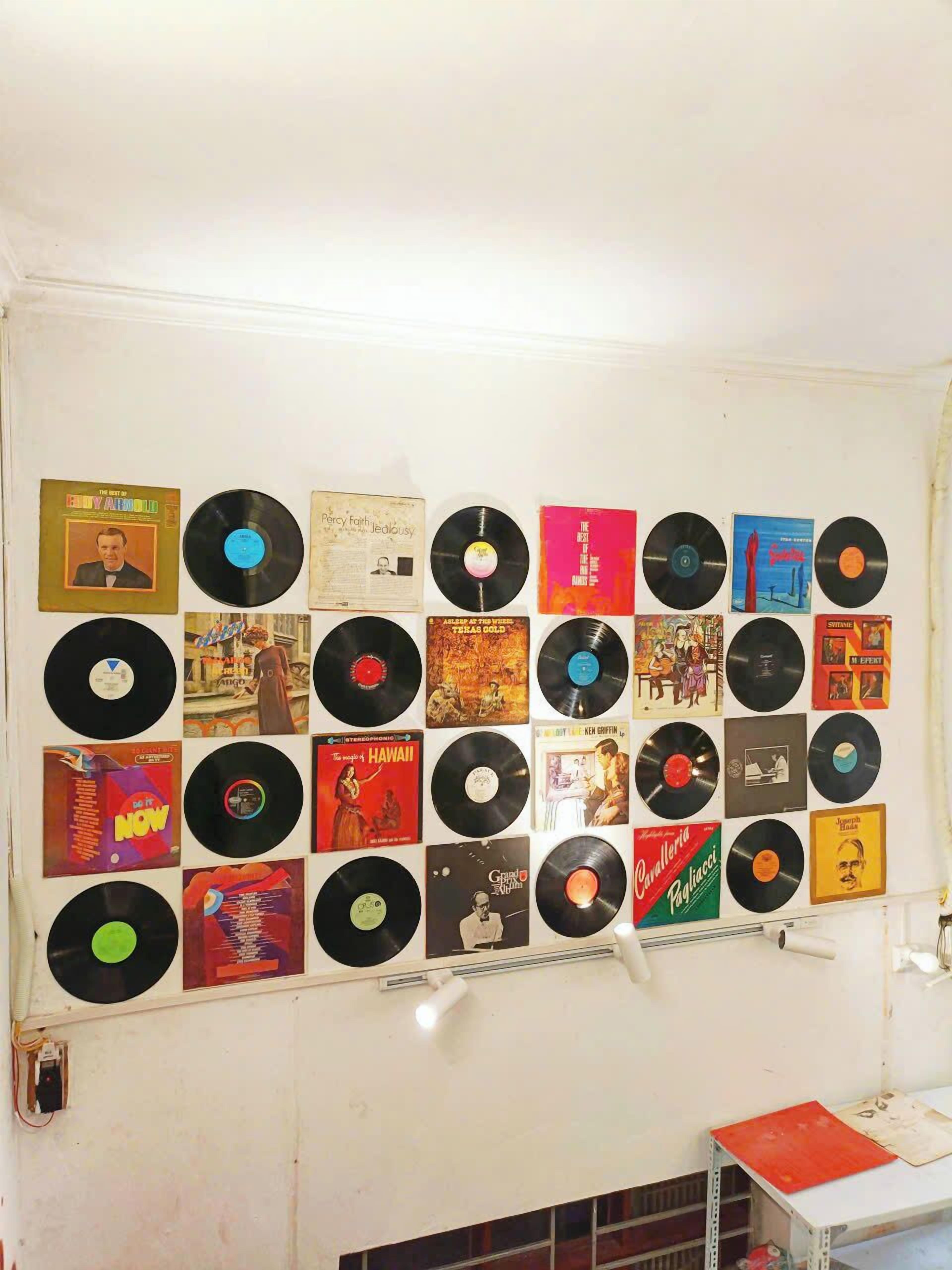 A wall with a collection of vinyl records and album covers arranged in a grid pattern.