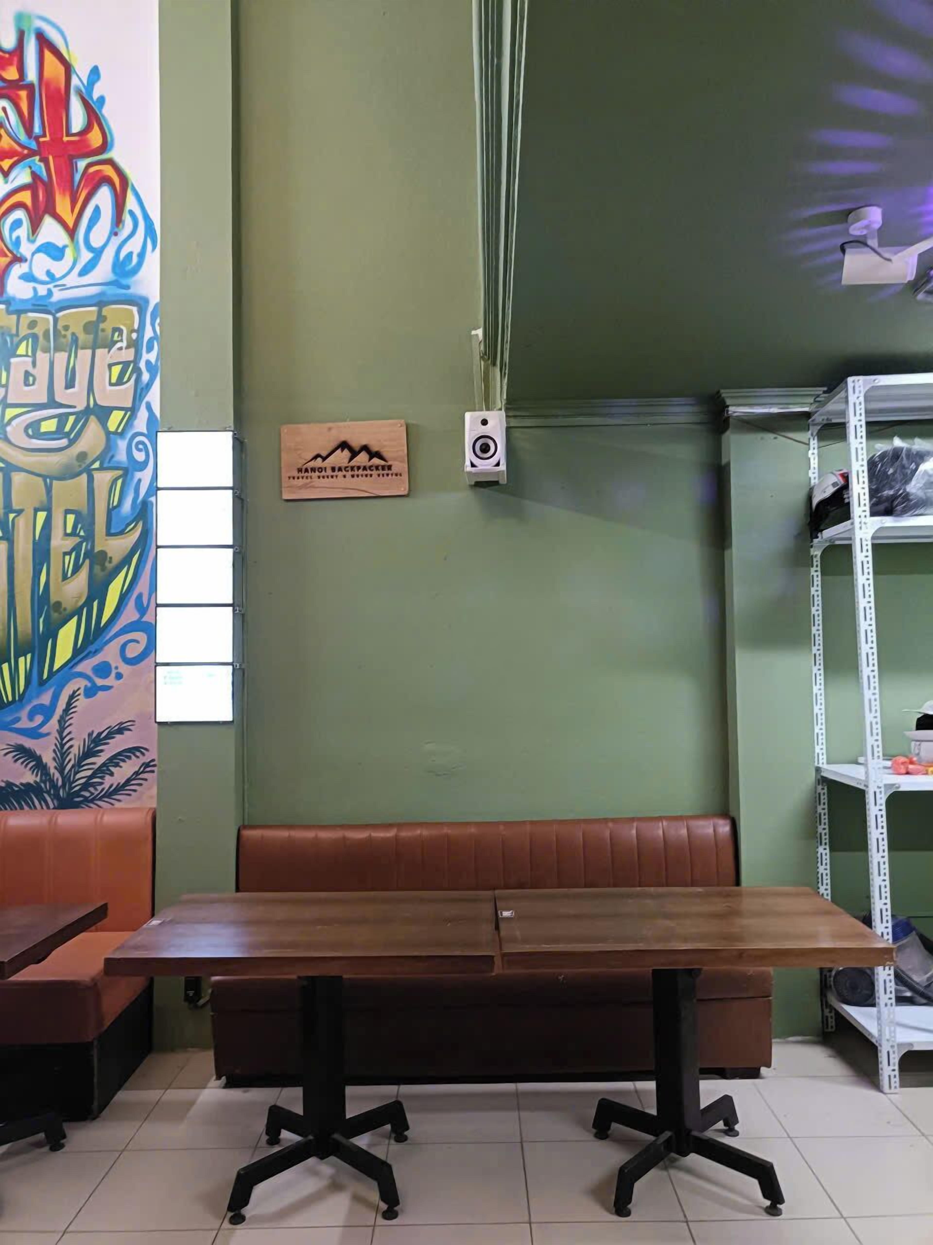 A restaurant with a booth seating area, a wooden table, and a wall with a colorful mural.