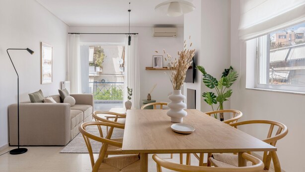 A modern living room with a sofa, a dining table with chairs, a floor lamp, and a view of the outside. - Ample 3BR Apartment II in Marousi (Marousi)