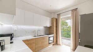 A modern kitchen with white cabinets, a marble backsplash, a built-in oven, and a large window with curtains. - Ample 3BR Apartment II in Marousi (Marousi)