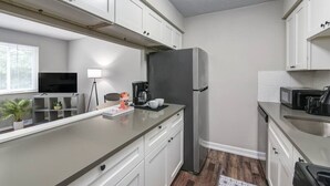 A modern kitchen with white cabinets, a stainless steel refrigerator, a coffee maker, and a microwave. - Modern 1BR | First Floor | Garage | Rocky River (Rocky River)