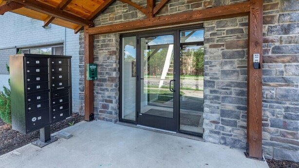 A building entrance with a stone facade, a wooden overhang, a mailbox, and a black mailbox unit. - Modern 1BR | First Floor | Garage | Rocky River (Rocky River)