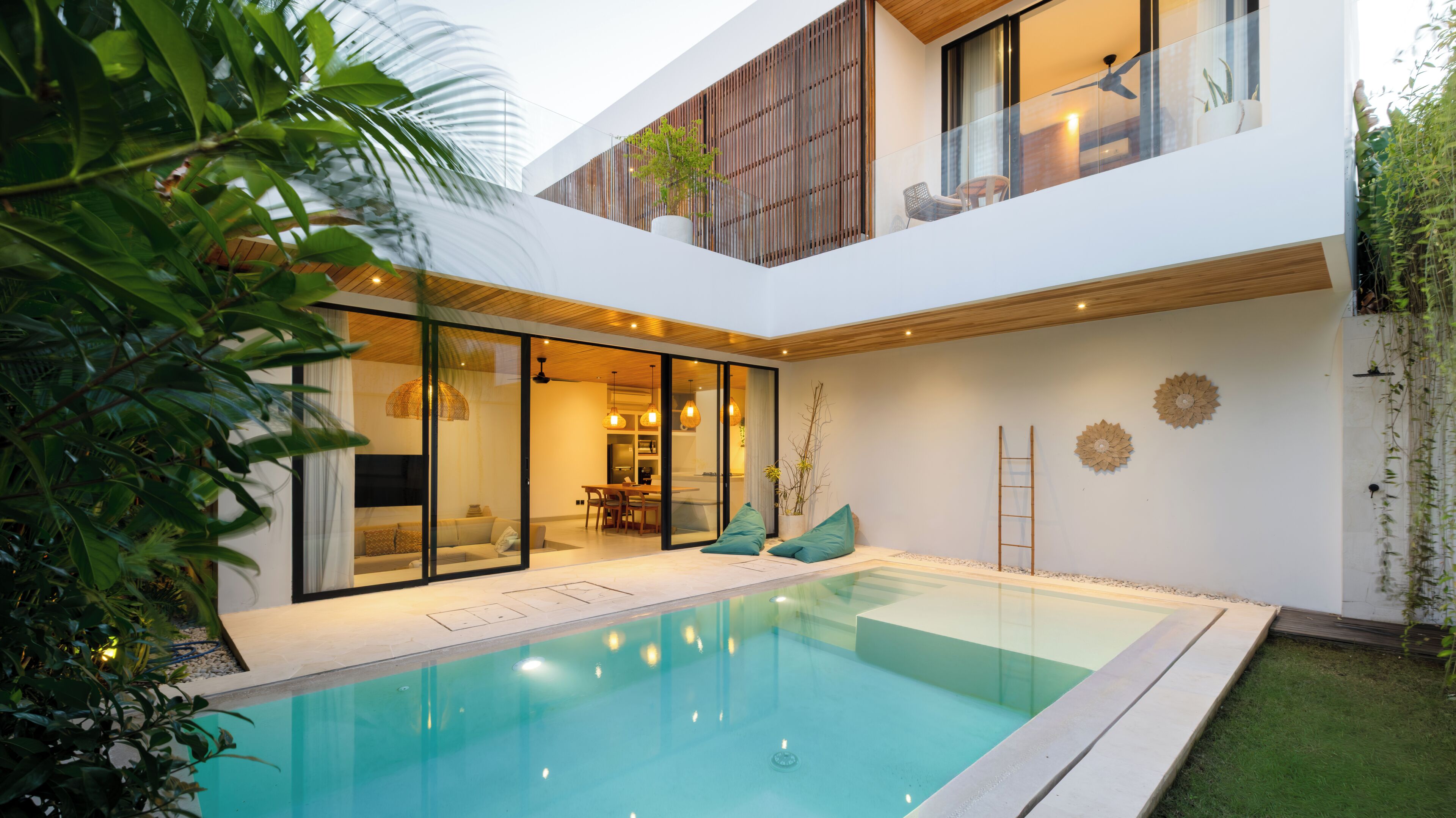 Une maison moderne dotée d’une piscine, de portes vitrées donnant sur un espace repas et d’une terrasse en bois.