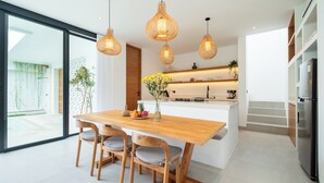 A modern kitchen with a wooden island, pendant lights, and a view to the outside. - Loona Palm Villas by Villa Finder (Canggu)