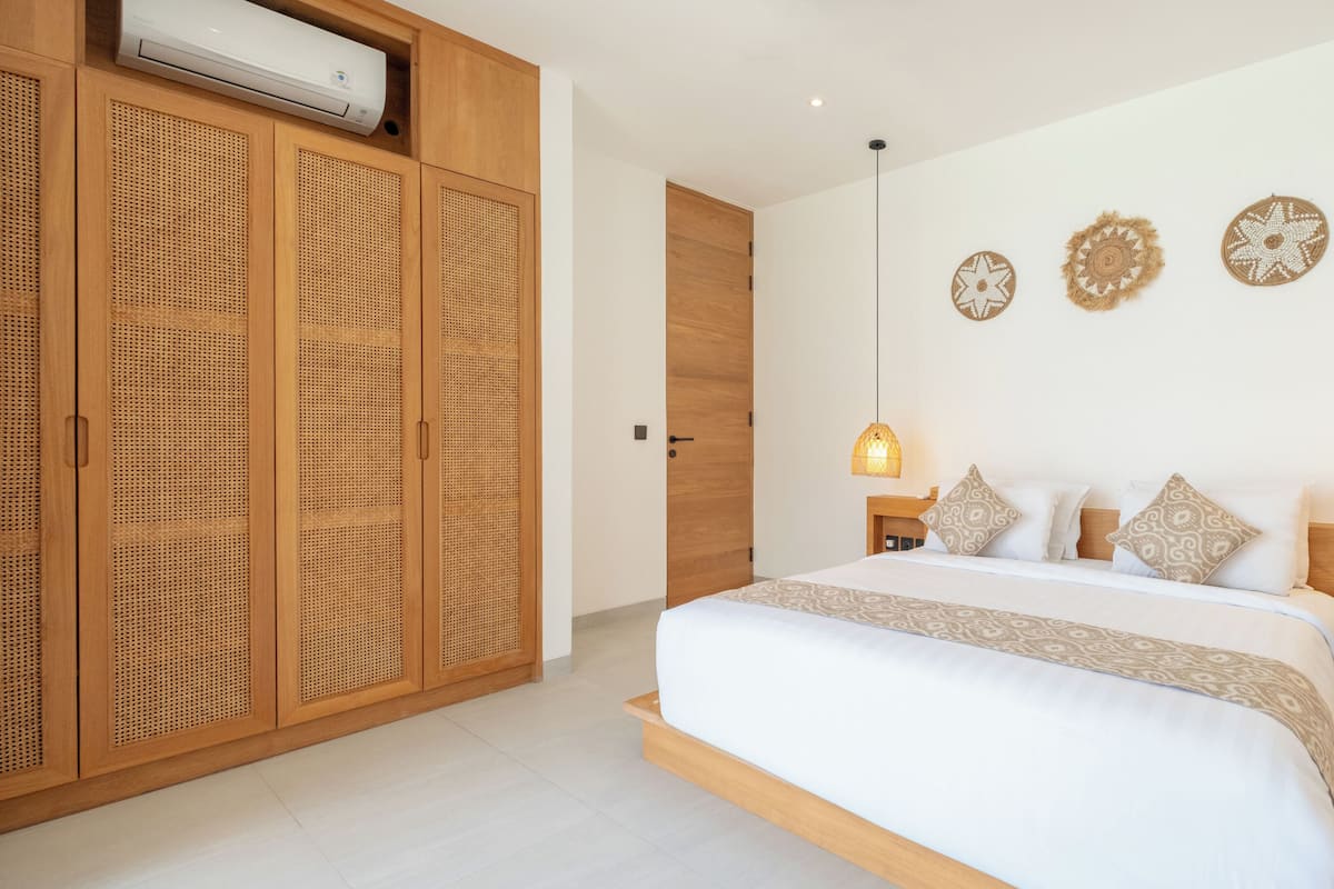 A bedroom with a large bed, wooden wardrobe, and decorative wall hangings.